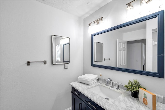 bathroom featuring baseboards, a textured ceiling, and vanity