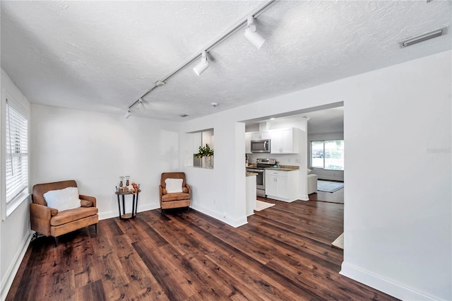 sitting room with track lighting, visible vents, dark wood-type flooring, and baseboards
