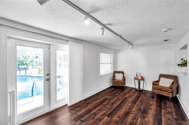 sitting room featuring track lighting, a healthy amount of sunlight, baseboards, a textured ceiling, and dark wood-style floors
