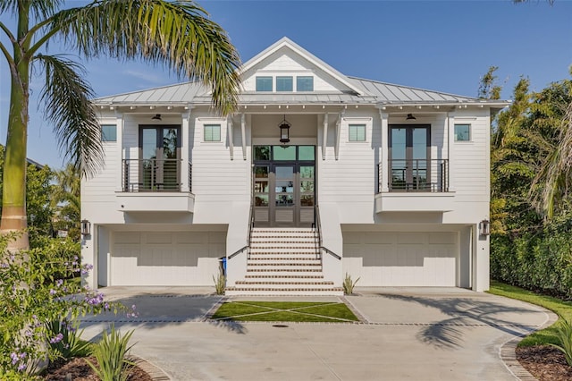 view of front of home with french doors, an attached garage, concrete driveway, and a balcony