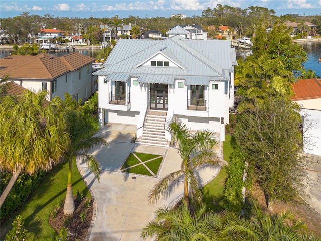 view of front of property with an attached garage, french doors, stairway, concrete driveway, and a standing seam roof