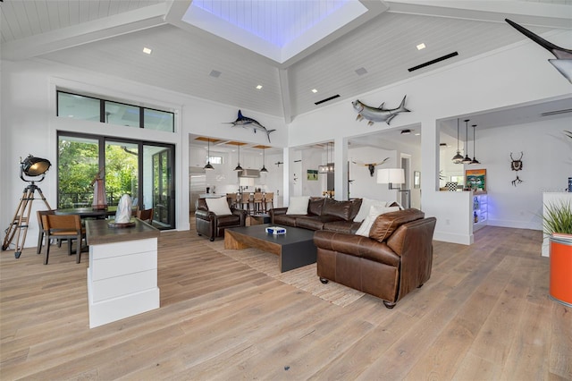 living area featuring beamed ceiling, recessed lighting, a high ceiling, and light wood-style floors