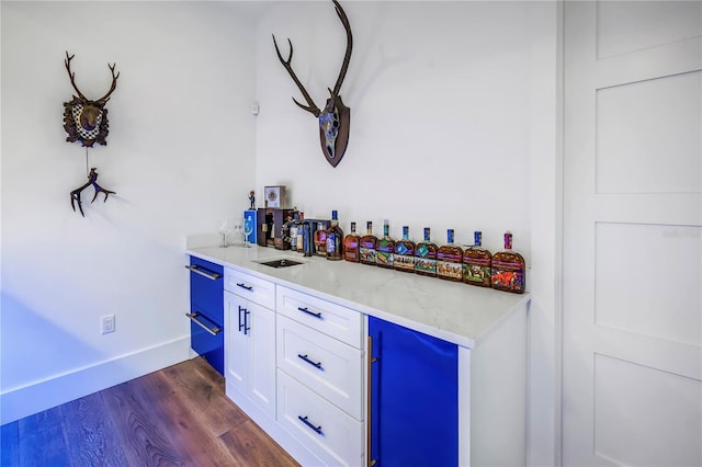 bar featuring baseboards, refrigerator, and dark wood-type flooring