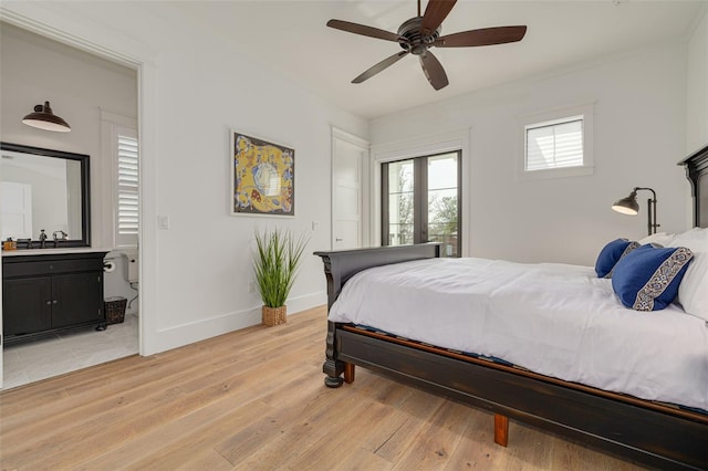bedroom with ceiling fan, a sink, ensuite bath, light wood-style floors, and baseboards