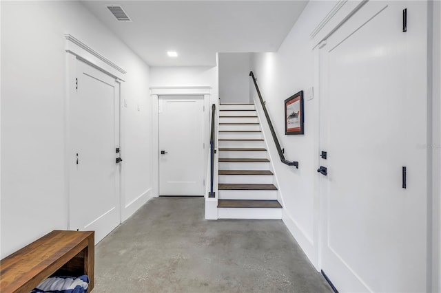 entryway featuring stairway, baseboards, concrete flooring, and visible vents