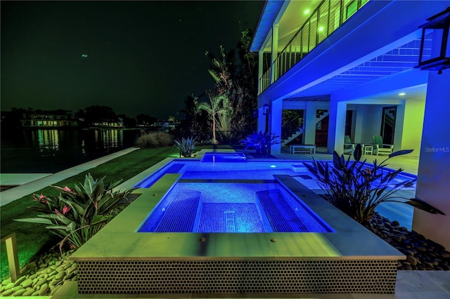 pool at night with an in ground hot tub and an outdoor pool