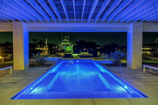pool at night with an outdoor pool and a patio area