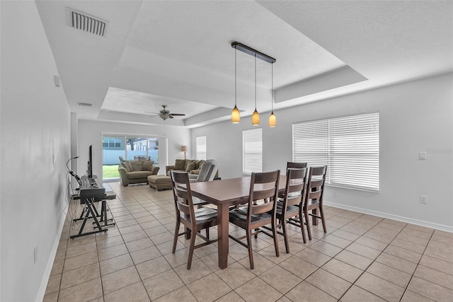 dining space with visible vents, baseboards, light tile patterned flooring, and a tray ceiling