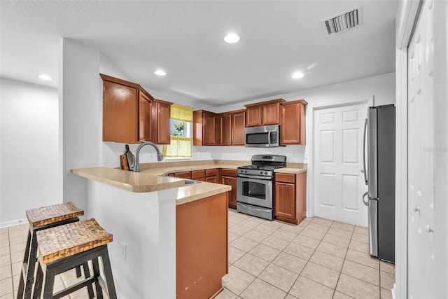 kitchen with visible vents, light tile patterned floors, light countertops, a peninsula, and stainless steel appliances