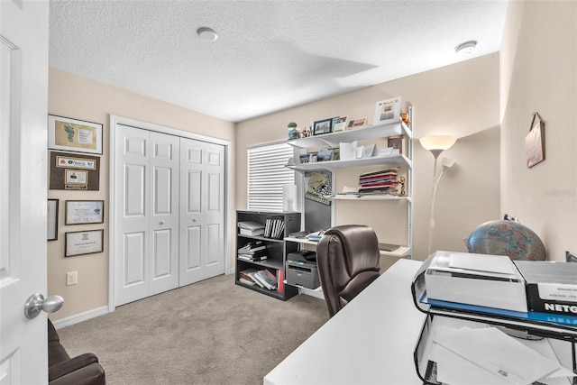 carpeted home office featuring a textured ceiling and baseboards