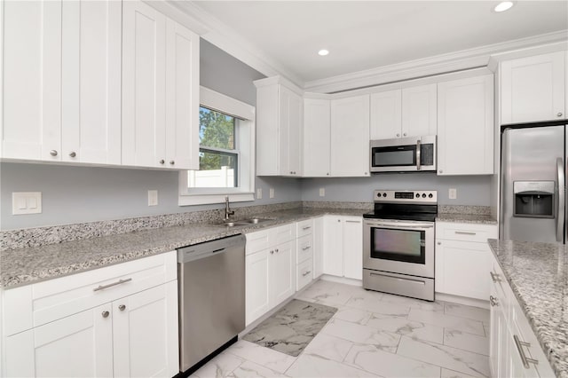 kitchen with appliances with stainless steel finishes, a sink, marble finish floor, white cabinetry, and ornamental molding