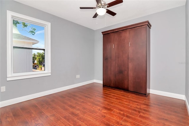unfurnished bedroom with baseboards, wood finished floors, and a closet