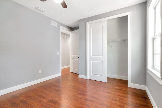 unfurnished bedroom with baseboards, a closet, wood finished floors, and visible vents