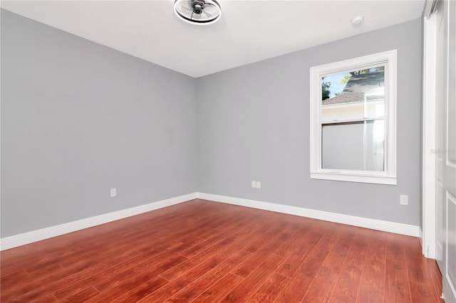 empty room with baseboards and dark wood finished floors