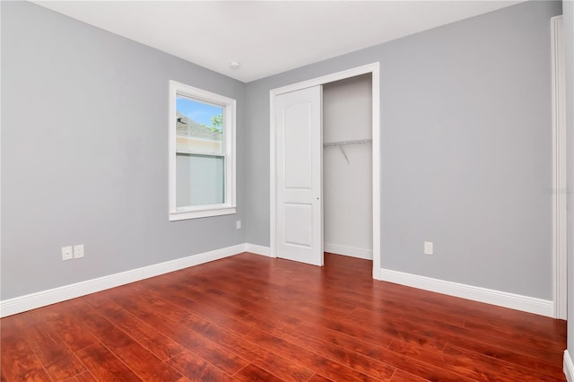 unfurnished bedroom featuring baseboards, a closet, and dark wood finished floors