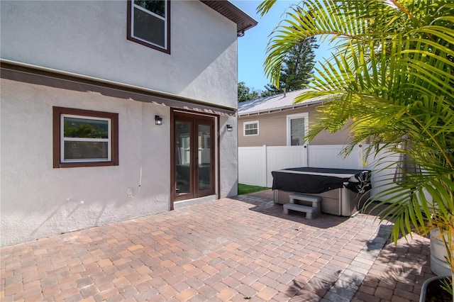 view of patio / terrace featuring french doors, fence, and a hot tub