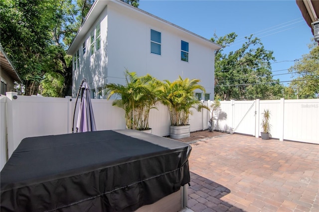 exterior space featuring a fenced backyard, a gate, a hot tub, and grilling area