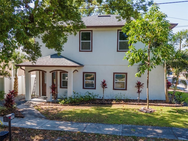 view of front of property with fence, a shingled roof, stucco siding, a porch, and a front yard
