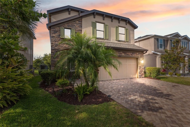 17537 Brighton Lake Rd, Land O Lakes, FL 34638 - view of front facade featuring stone siding, stucco siding, an attached garage, and decorative driveway