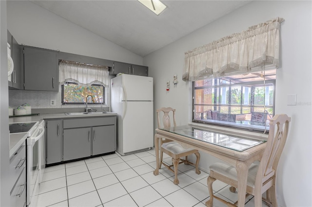 kitchen with a sink, white appliances, plenty of natural light, gray cabinets, and lofted ceiling