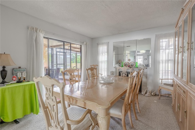 dining area with a textured ceiling and light colored carpet