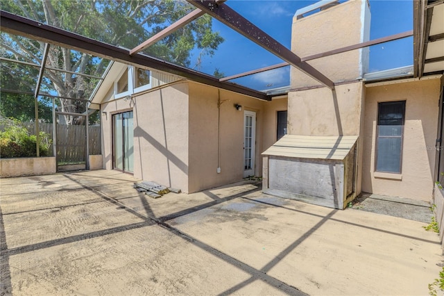 back of property with glass enclosure, a patio, and stucco siding