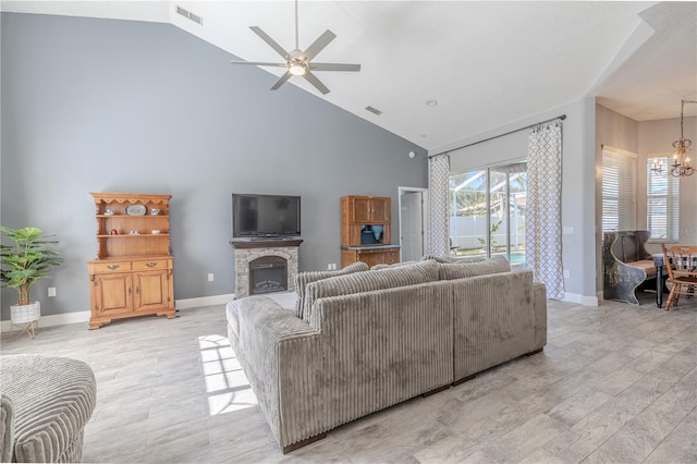living area featuring light wood-style floors, high vaulted ceiling, ceiling fan with notable chandelier, and visible vents
