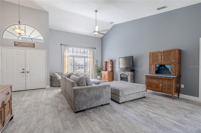 living area with a ceiling fan, visible vents, high vaulted ceiling, baseboards, and light wood finished floors