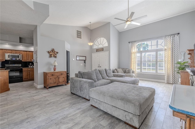 living area with visible vents, baseboards, ceiling fan, high vaulted ceiling, and light wood-style flooring