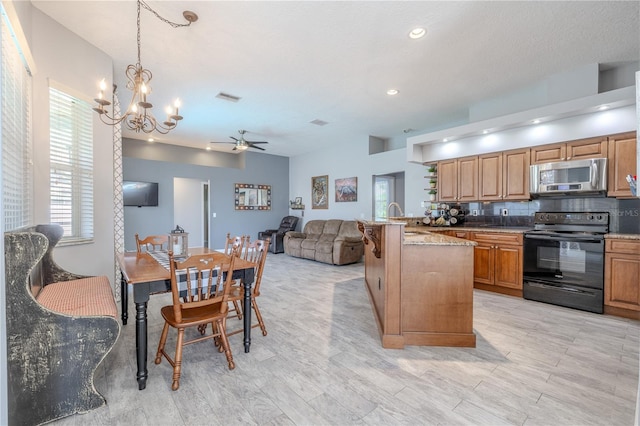 kitchen with visible vents, black electric range oven, a sink, stainless steel microwave, and ceiling fan with notable chandelier