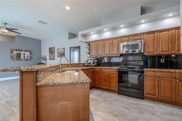 kitchen with brown cabinets, a sink, black electric range, a peninsula, and stainless steel microwave