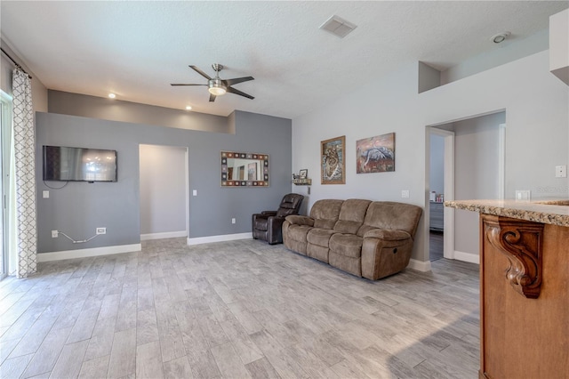living area featuring visible vents, baseboards, ceiling fan, a textured ceiling, and light wood finished floors