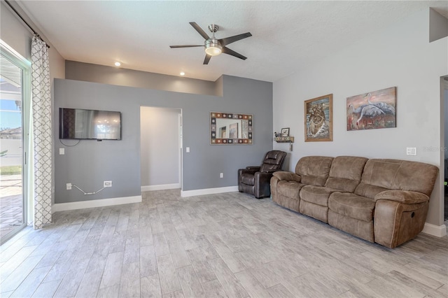 living room with baseboards, ceiling fan, and light wood finished floors