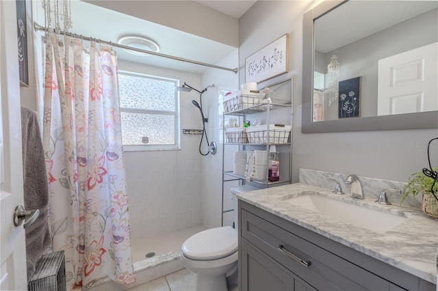 bathroom with toilet, tiled shower, and vanity
