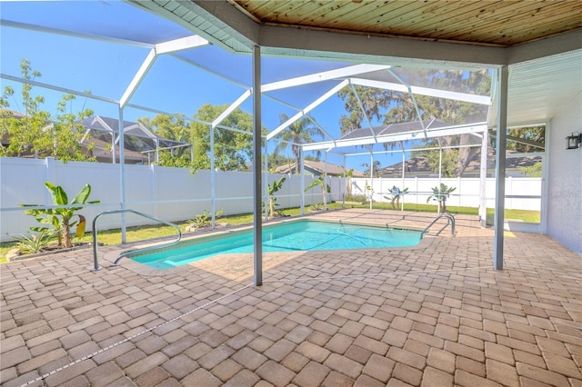view of swimming pool featuring glass enclosure, a patio, a fenced in pool, and a fenced backyard