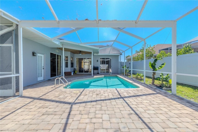 view of pool with fence, a fenced in pool, a patio area, a ceiling fan, and glass enclosure