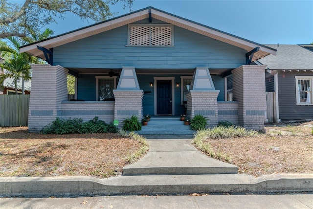 view of front facade featuring fence, covered porch, and brick siding