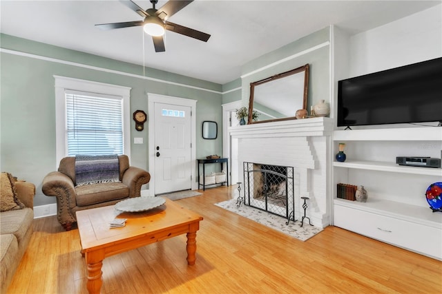 living area with ceiling fan, a fireplace, and wood finished floors