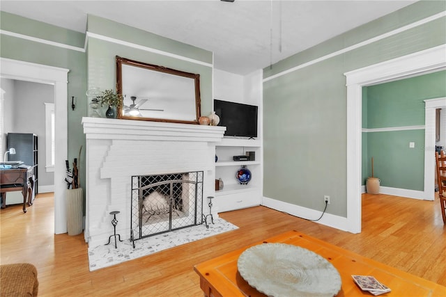 living room featuring baseboards, ceiling fan, wood finished floors, and a fireplace