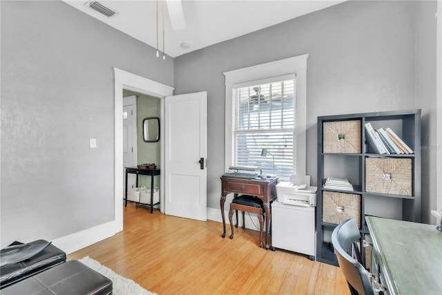 home office featuring baseboards, a ceiling fan, wood finished floors, and visible vents