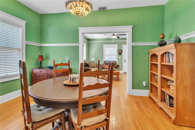 dining room featuring baseboards, a ceiling fan, light wood-style flooring, and visible vents