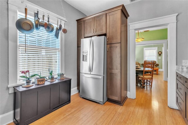 kitchen featuring baseboards, light wood-style flooring, and stainless steel fridge with ice dispenser