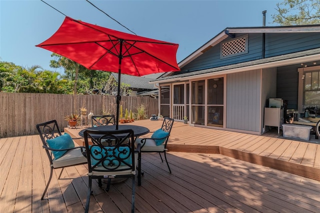 wooden deck featuring fence, outdoor dining area, and a sunroom