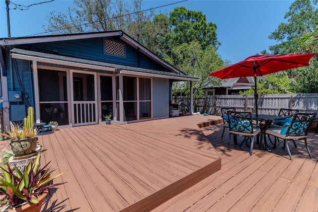 wooden deck featuring a fenced backyard, outdoor dining area, and a sunroom