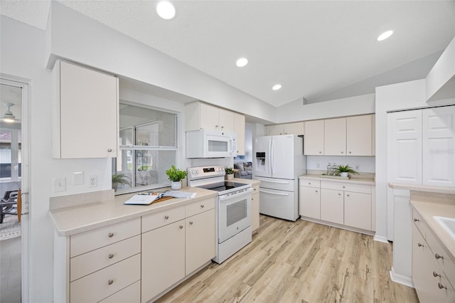 11218 Sun Tree Rd, Hudson, FL 34667 - kitchen with white appliances, vaulted ceiling, light wood-type flooring, white cabinets, and light countertops