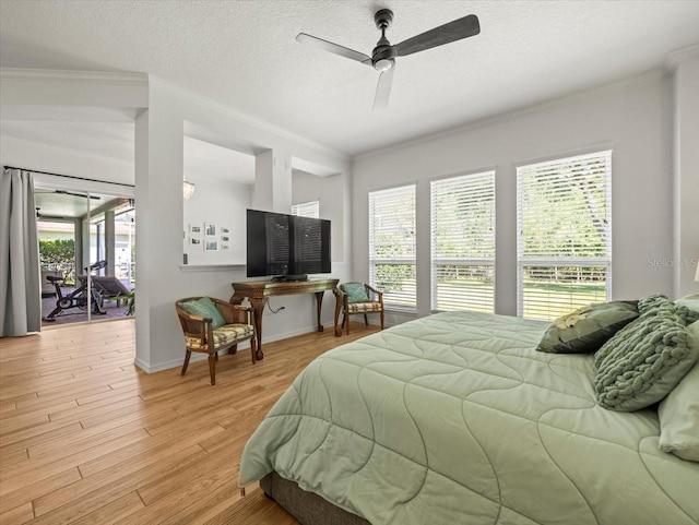 bedroom with ornamental molding, a textured ceiling, baseboards, and light wood-style floors