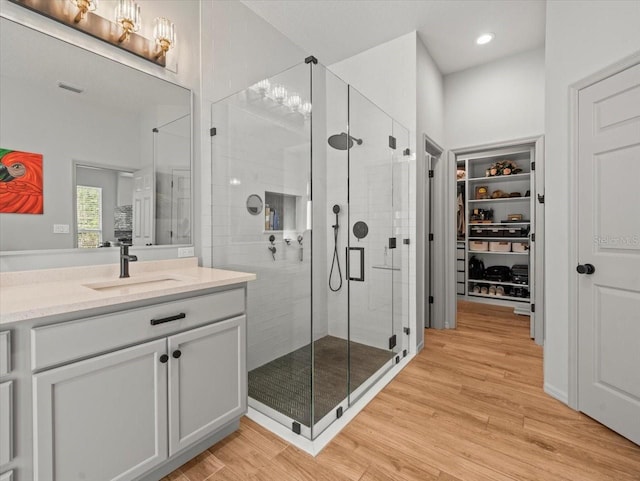 full bath featuring wood finished floors, a shower stall, recessed lighting, and vanity