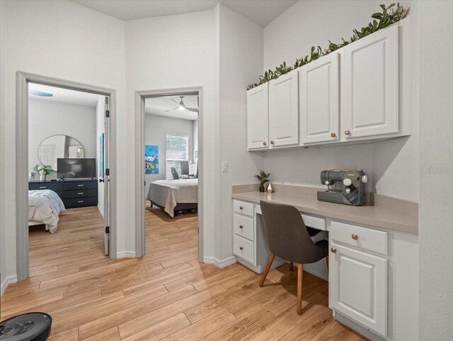 home office featuring light wood-style floors, built in desk, and baseboards