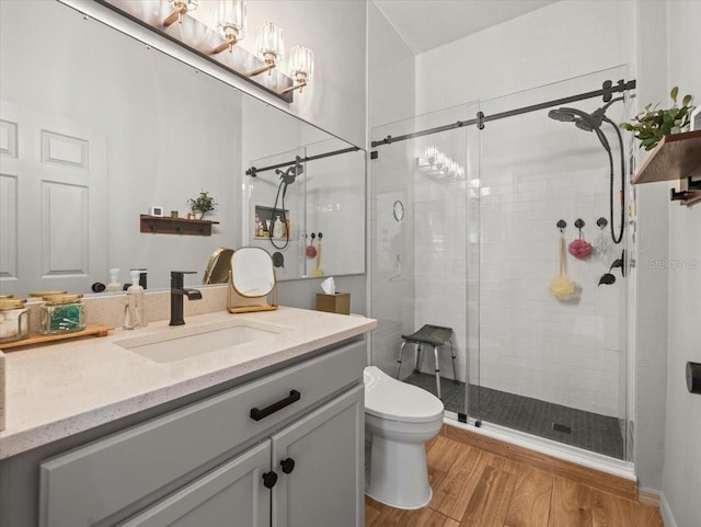 bathroom featuring a shower stall, vanity, a chandelier, toilet, and wood finished floors