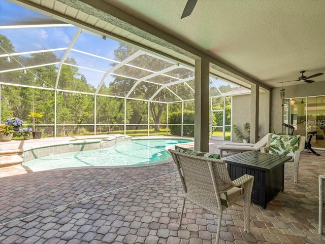 view of swimming pool with a lanai, a ceiling fan, a pool with connected hot tub, and a patio area